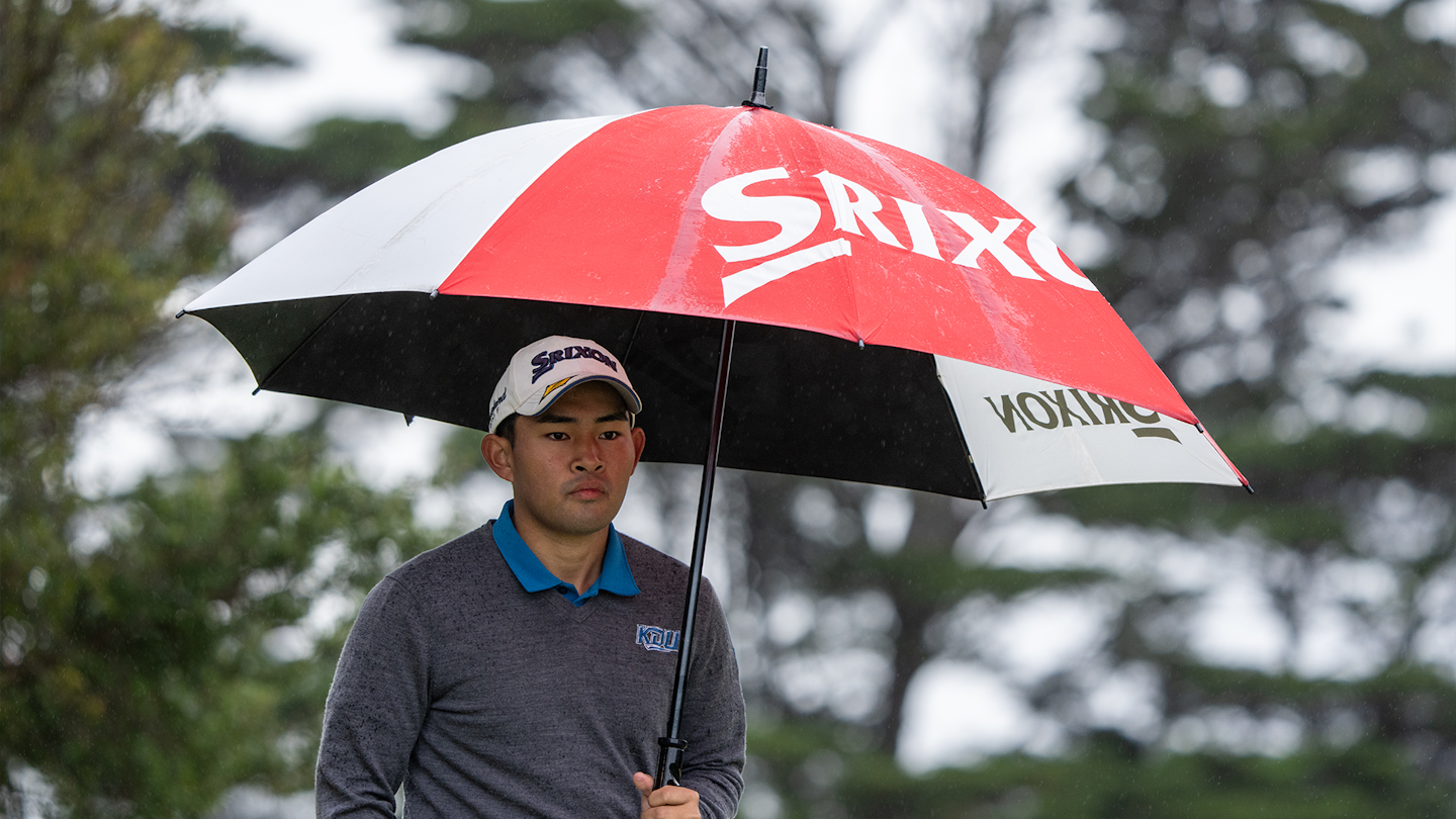 Masayuki Yamashita of Japan shelters under an umbrella during the first round of the 2023 Asia-Pacific Amateur Championship