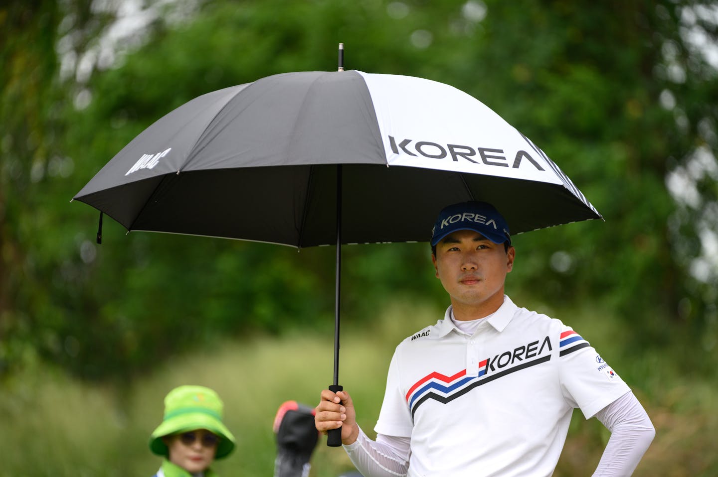 Wooyoung Cho of Korea shelters under an umbrella